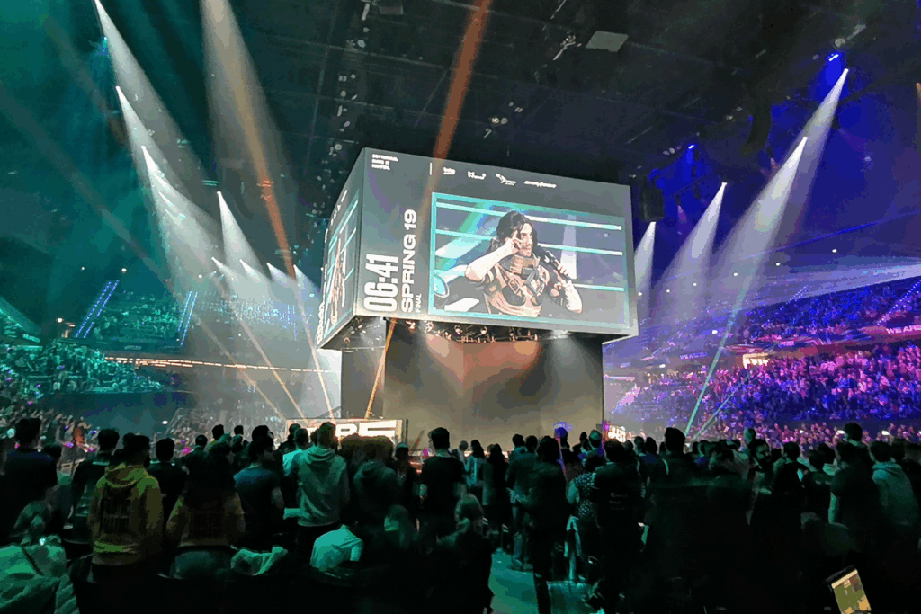 A massive audience watches the League of Legends finals, with bright stage lights illuminating the excitement in Paris.